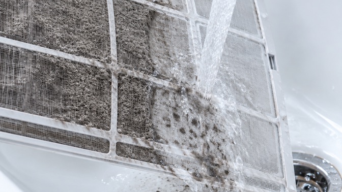 Filtre de climatisation encrassé rincé sous le robinet
